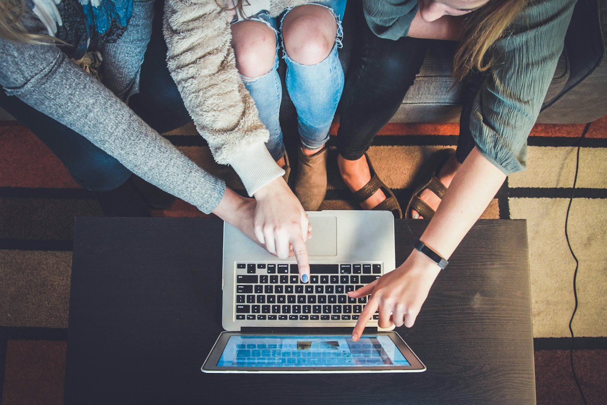 Three people gathered around a laptop